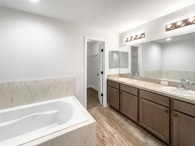 bathroom with hardwood / wood-style floors, vanity, and tiled bath