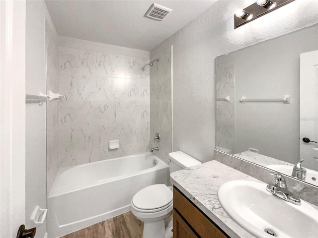 full bathroom with tiled shower / bath combo, toilet, wood-type flooring, and vanity