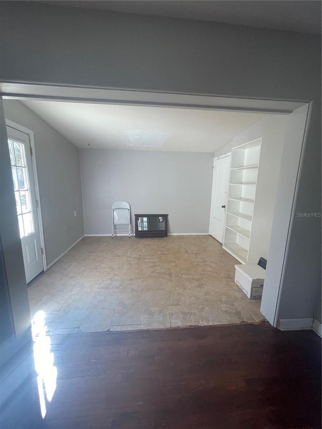 spare room featuring baseboards, wood finished floors, and built in features