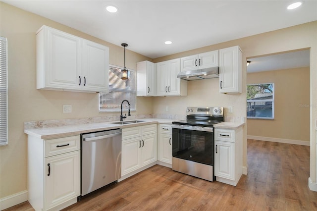 kitchen featuring appliances with stainless steel finishes, sink, pendant lighting, light hardwood / wood-style flooring, and white cabinets