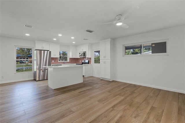 kitchen featuring white cabinetry, a center island, ceiling fan, stainless steel appliances, and light wood-type flooring