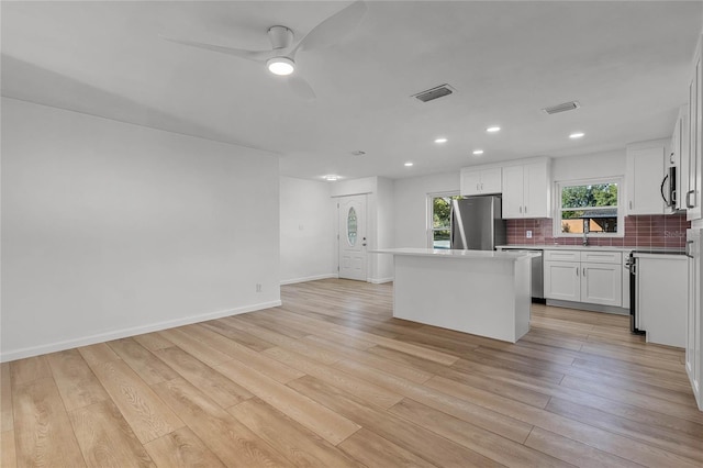 kitchen featuring white cabinetry, a center island, ceiling fan, tasteful backsplash, and appliances with stainless steel finishes