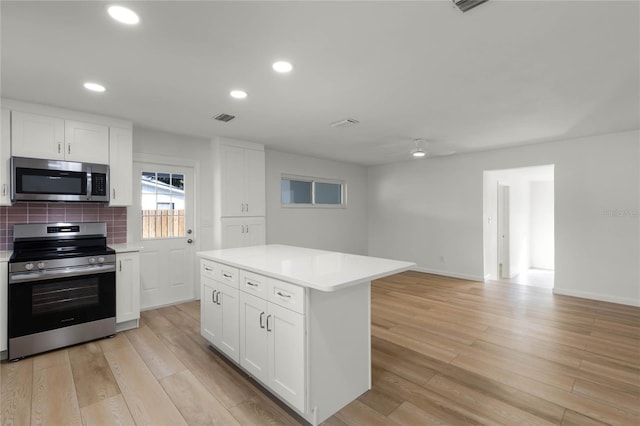 kitchen with a center island, white cabinetry, appliances with stainless steel finishes, and tasteful backsplash