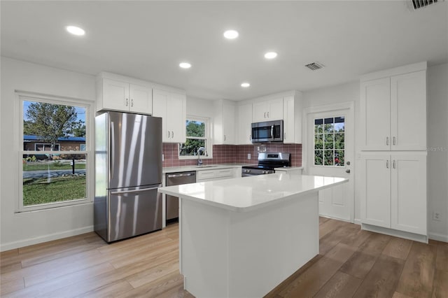 kitchen with a center island, white cabinets, stainless steel appliances, and sink