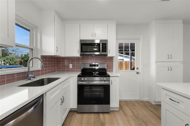 kitchen featuring white cabinets, backsplash, sink, and appliances with stainless steel finishes