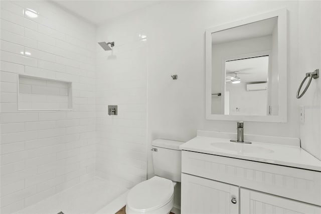 bathroom with ceiling fan, an AC wall unit, tiled shower, toilet, and vanity