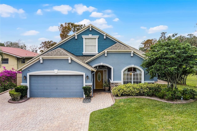 view of front of home with a garage, roof with shingles, decorative driveway, a front lawn, and stucco siding