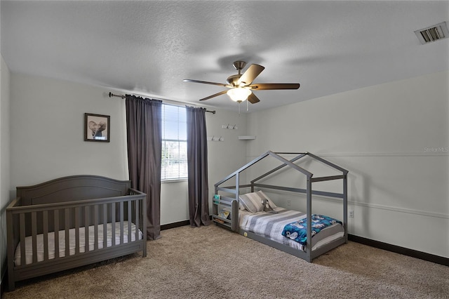 carpeted bedroom with a ceiling fan, visible vents, a textured ceiling, and baseboards