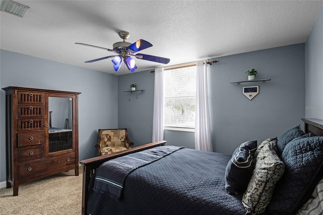 bedroom with ceiling fan, light carpet, and a textured ceiling