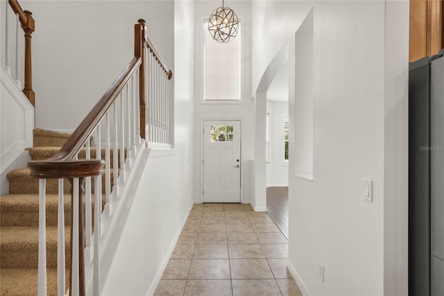 tiled entryway with a chandelier