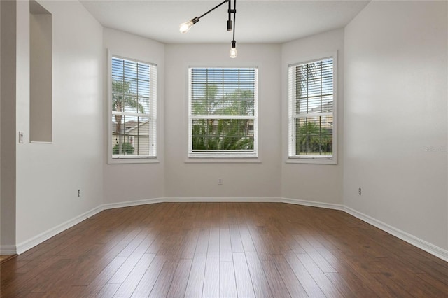 empty room featuring a chandelier and dark wood-type flooring