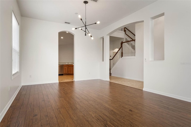 empty room featuring a chandelier, dark hardwood / wood-style floors, and a healthy amount of sunlight