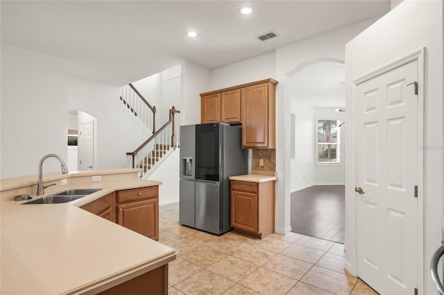 kitchen with tasteful backsplash, sink, light tile patterned flooring, and stainless steel refrigerator with ice dispenser