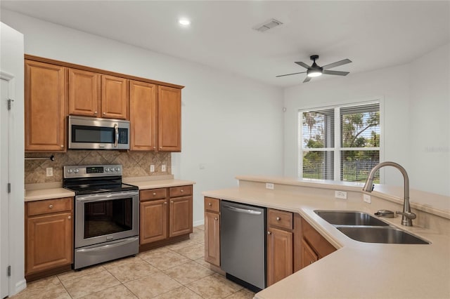 kitchen featuring ceiling fan, sink, stainless steel appliances, tasteful backsplash, and light tile patterned floors