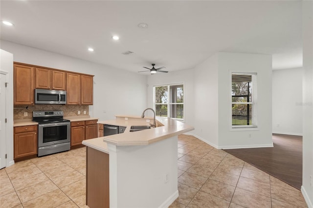 kitchen with stainless steel appliances, ceiling fan, sink, an island with sink, and light tile patterned flooring