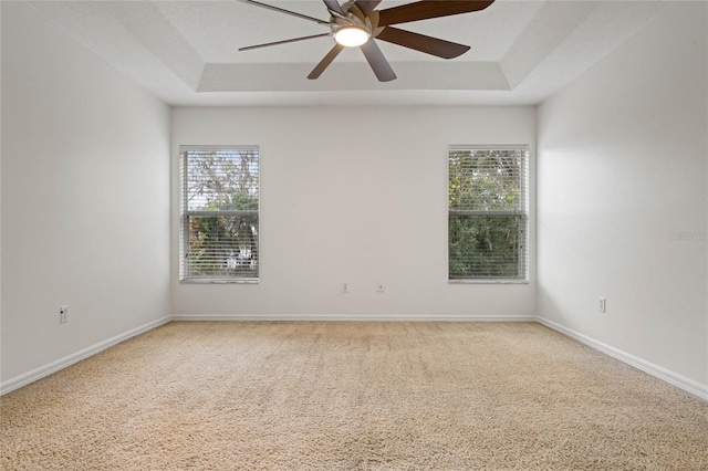 unfurnished room featuring carpet flooring, plenty of natural light, ceiling fan, and a tray ceiling