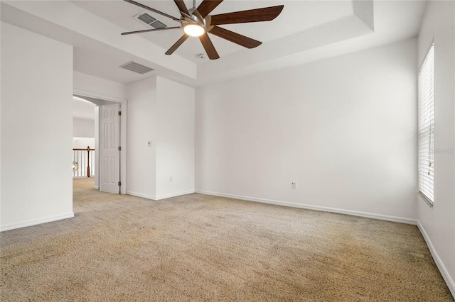 carpeted empty room featuring a raised ceiling and ceiling fan