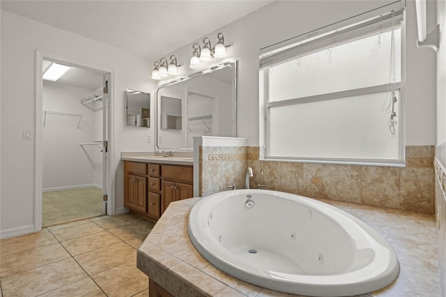 bathroom with tile patterned flooring, vanity, and a relaxing tiled tub