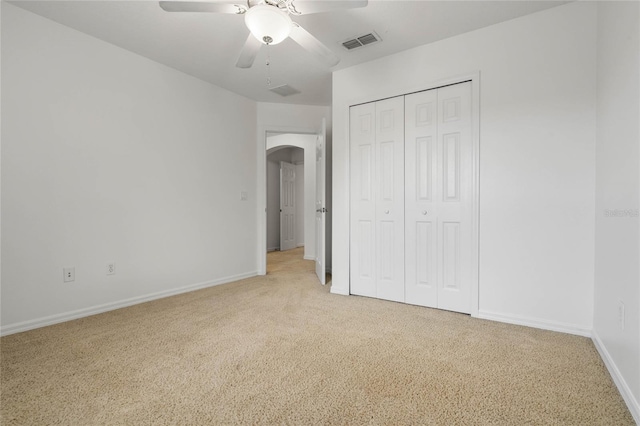 unfurnished bedroom featuring light carpet, a closet, and ceiling fan