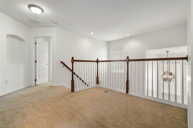 carpeted spare room with an inviting chandelier