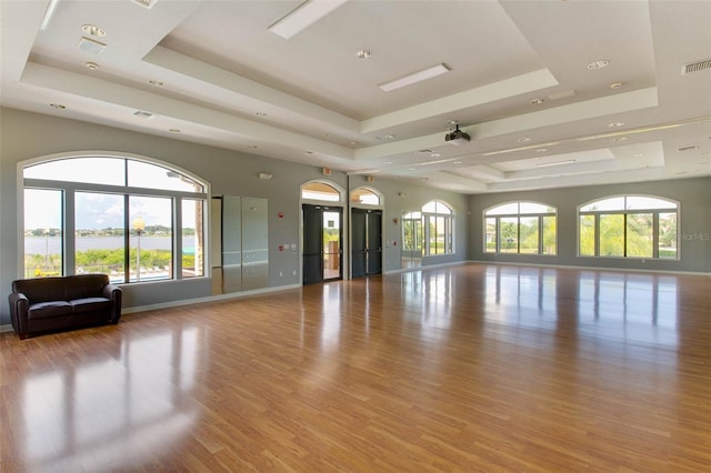 interior space featuring light hardwood / wood-style floors, elevator, and a tray ceiling