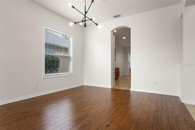 empty room featuring a chandelier and dark hardwood / wood-style flooring