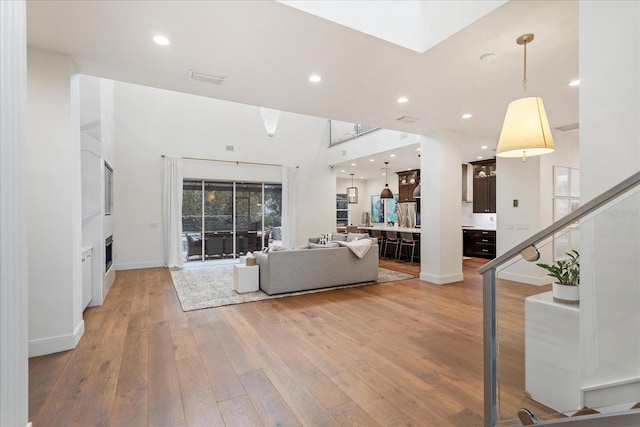 unfurnished living room featuring a towering ceiling and light hardwood / wood-style flooring