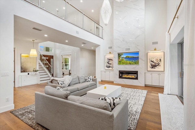 living room with a high ceiling, light hardwood / wood-style floors, and a premium fireplace