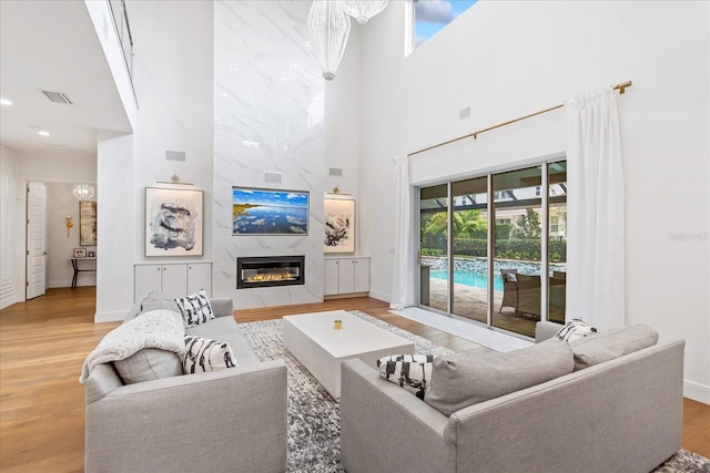 living room featuring a high ceiling, a high end fireplace, and light hardwood / wood-style flooring