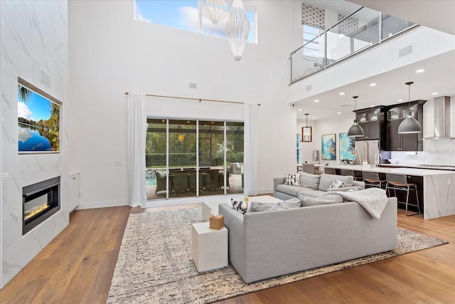 living room featuring a tile fireplace, a high ceiling, and light wood-type flooring