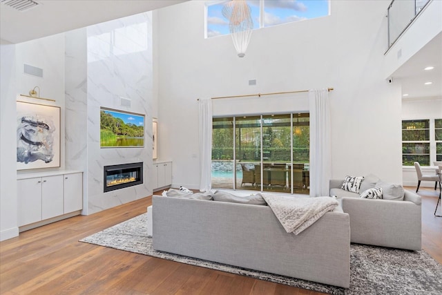 living room featuring hardwood / wood-style flooring, a towering ceiling, and a fireplace