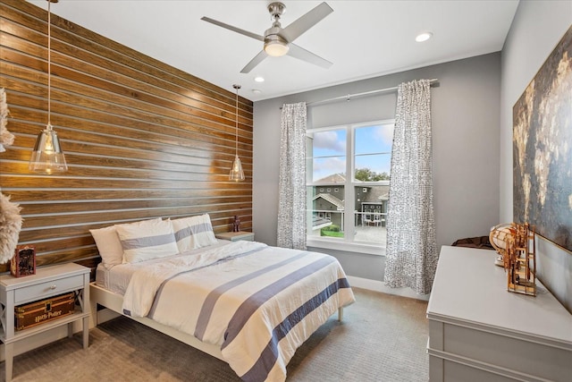 bedroom featuring dark colored carpet, ceiling fan, and wooden walls