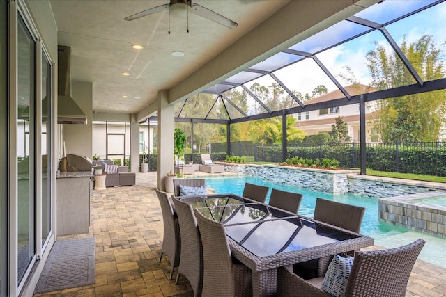 view of patio / terrace with glass enclosure, ceiling fan, and an outdoor kitchen