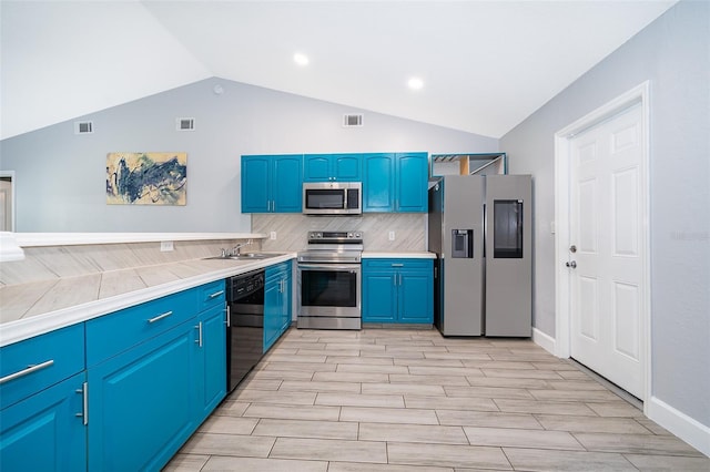 kitchen with decorative backsplash, stainless steel appliances, vaulted ceiling, and blue cabinetry