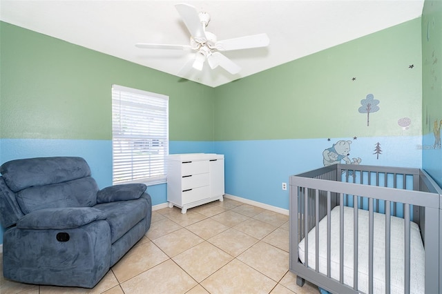 bedroom with ceiling fan, a crib, and light tile patterned floors