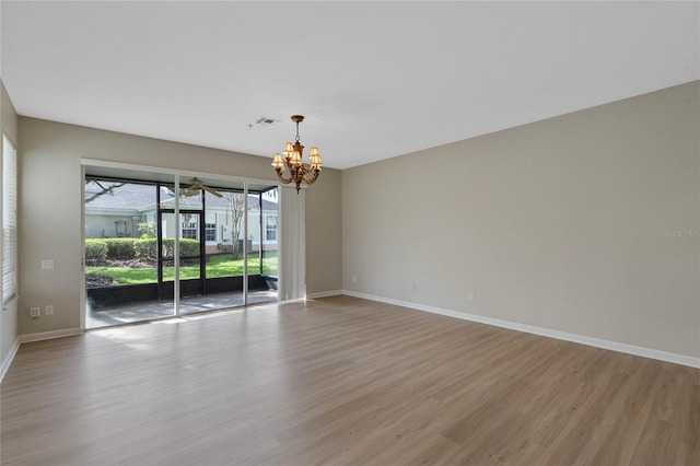 empty room with an inviting chandelier and light hardwood / wood-style flooring