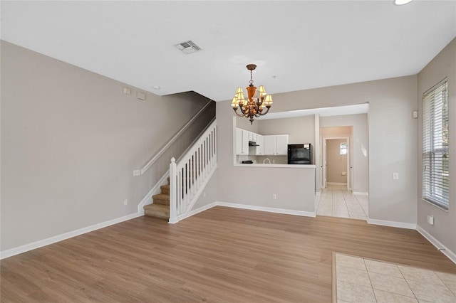 unfurnished living room featuring light hardwood / wood-style floors and an inviting chandelier