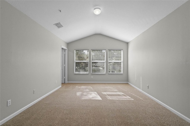 carpeted spare room featuring vaulted ceiling