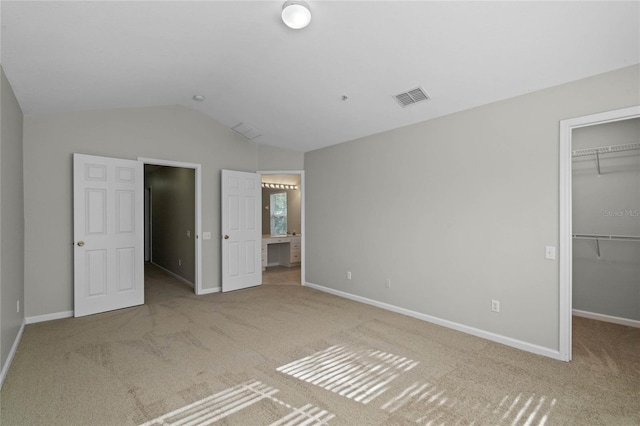 unfurnished bedroom featuring carpet flooring, a spacious closet, connected bathroom, a closet, and lofted ceiling