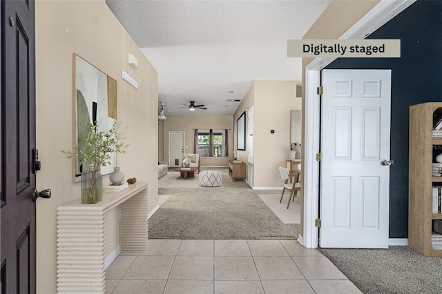 foyer entrance with light tile patterned floors, light colored carpet, a ceiling fan, and a textured ceiling