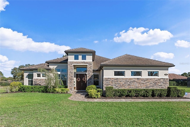 prairie-style home featuring stone siding, a front lawn, and stucco siding