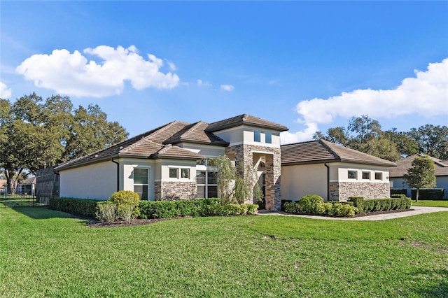 prairie-style home featuring stone siding, a tile roof, a front yard, and stucco siding