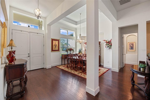 foyer featuring a notable chandelier, wood-type flooring, visible vents, a towering ceiling, and baseboards