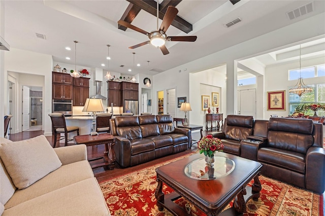 living area featuring beamed ceiling, light wood-type flooring, and visible vents