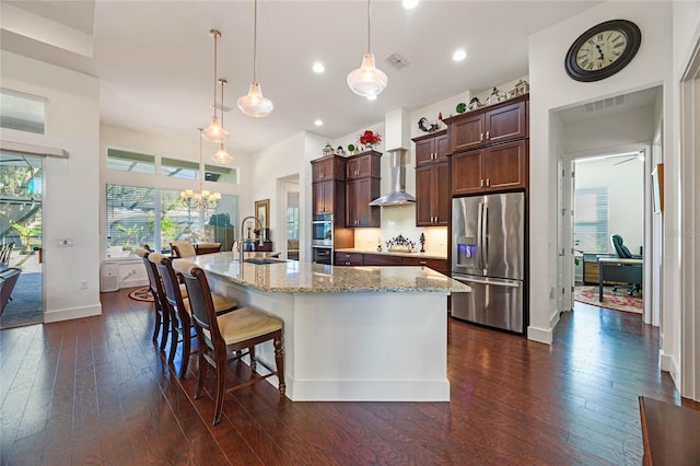 kitchen with visible vents, appliances with stainless steel finishes, dark wood-type flooring, a large island with sink, and a sink