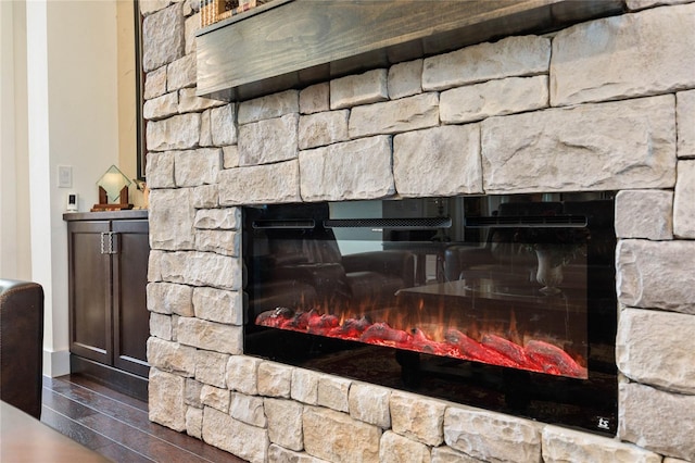 room details with a stone fireplace and wood finished floors