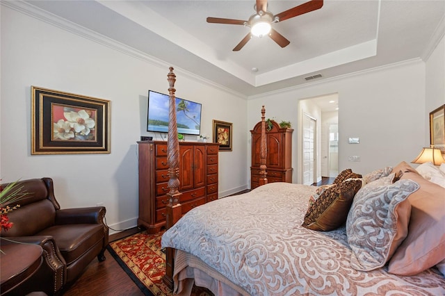 bedroom featuring wood finished floors, a raised ceiling, visible vents, and baseboards