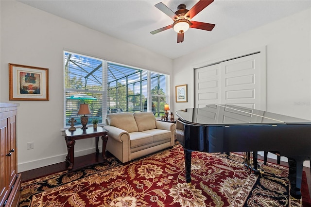 sitting room with a ceiling fan, baseboards, a sunroom, and wood finished floors