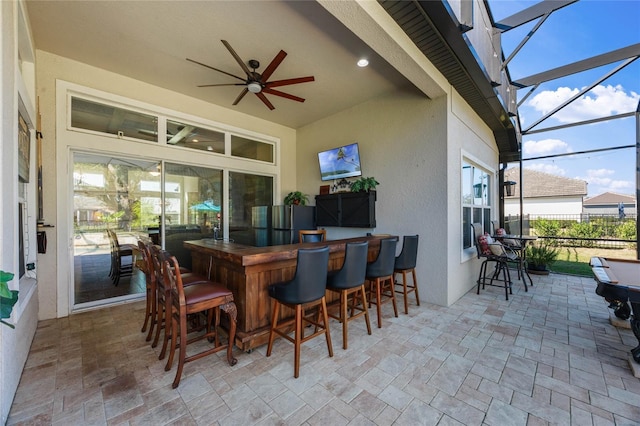 view of patio with a ceiling fan, glass enclosure, and outdoor dry bar