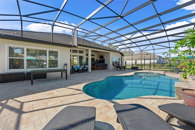 pool with a lanai, a patio area, and a ceiling fan